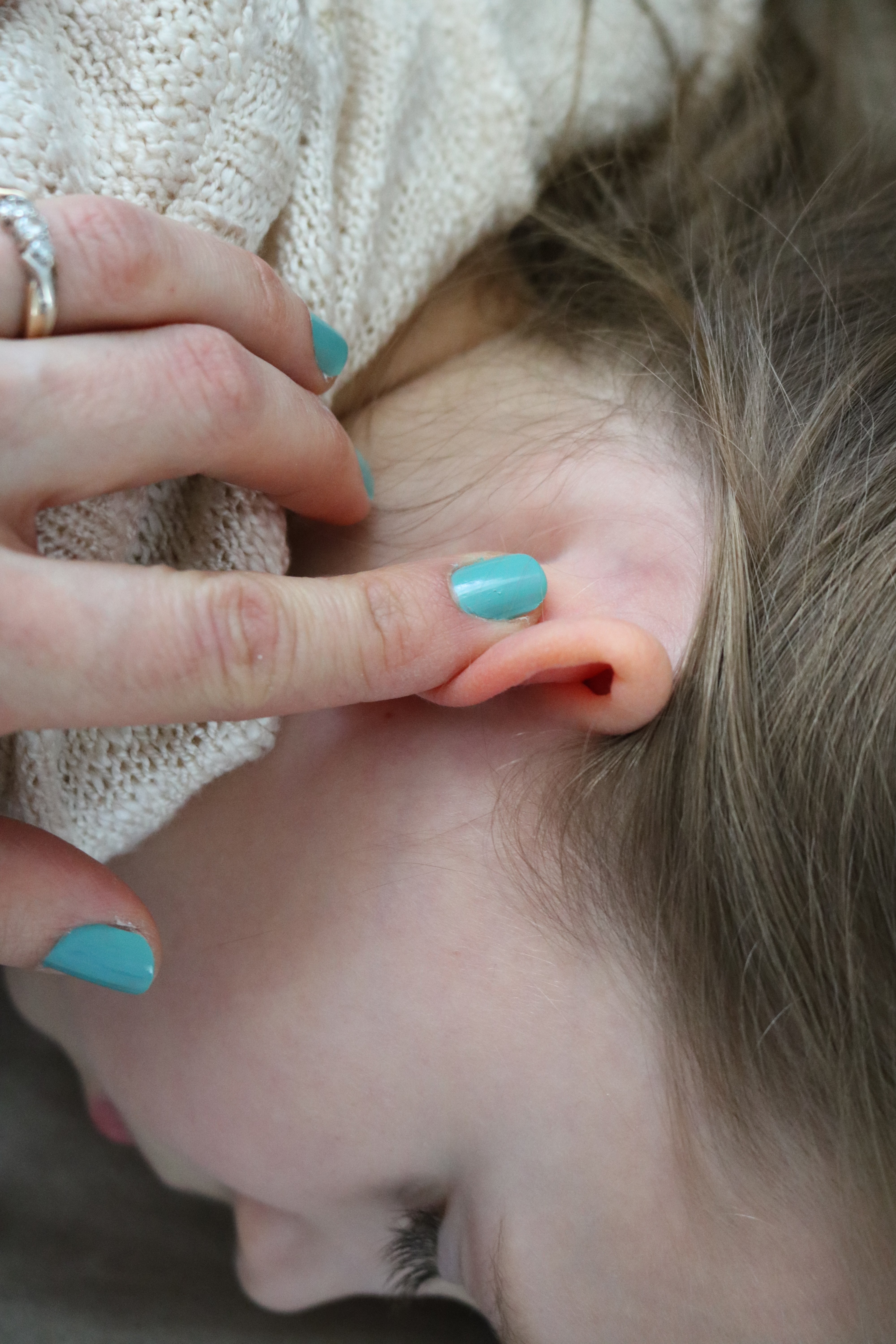 Bending ear forward to check for ear infection or earache in infants and/or babies.